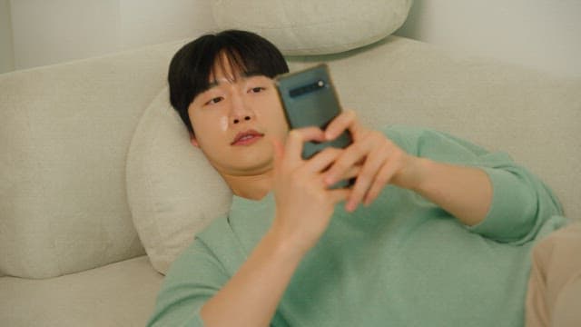 Man lounging on a couch using a smartphone