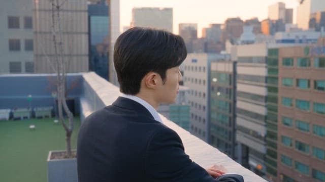 Man in a suit looking at buildings from a rooftop