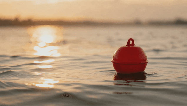 일몰에 잔잔한 바다에 떠 있는 빨간 부표