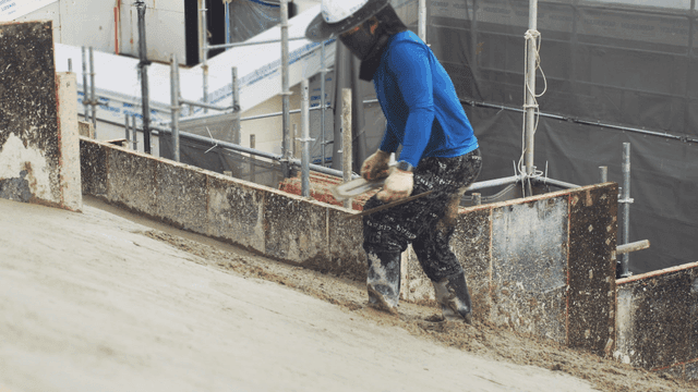 경사면에서 콘크리트를 다듬는 작업자