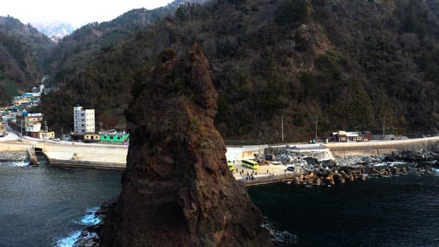 Coastal town with towering rock formations and buses