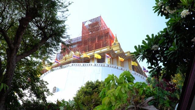 Temple under renovation with flags and trees around