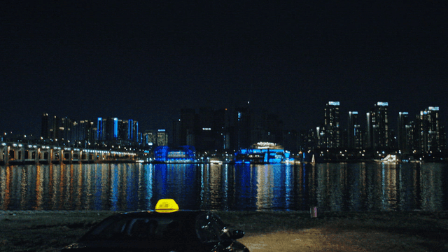 Taxi descending to riverside under night city skyline