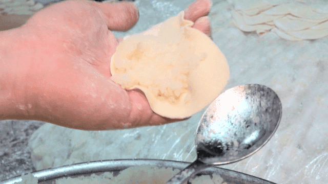 Spoon quickly filling minced glass noodles into dumpling wrapper