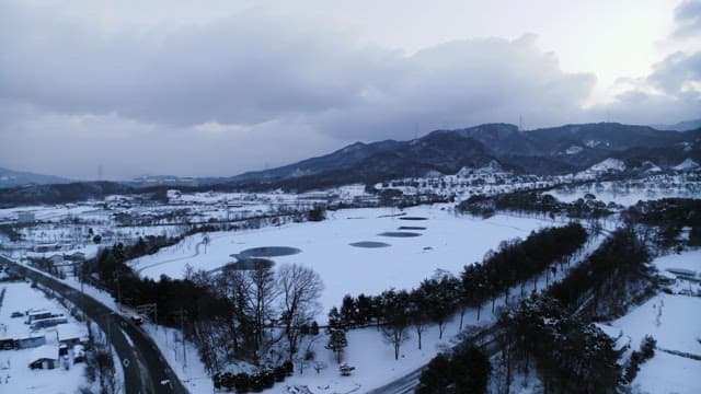 Snowy Landscape with Frozen Ponds Amidst Mountains