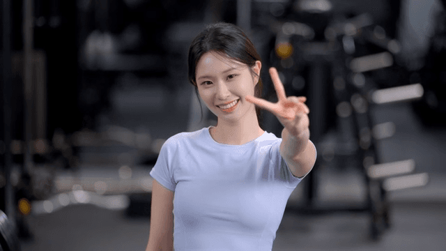 헬스장에서 정면을 보고 브이표시를 하며 미소 짓는 여성