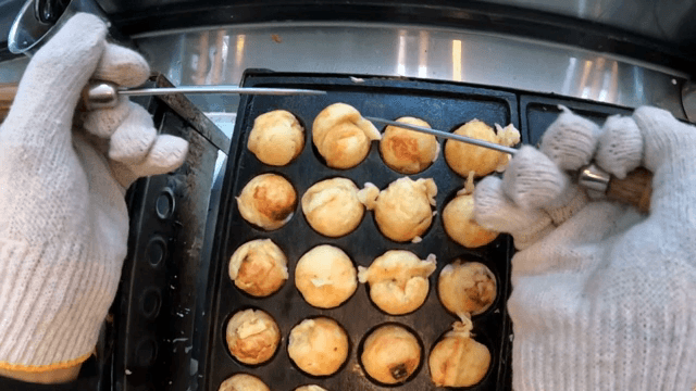 Cooking octopus balls on a hot griddle