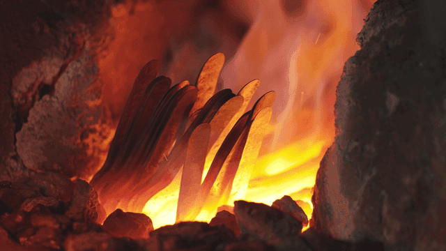 대장간에서 가열된 금속 조각을 꺼내는 작업자