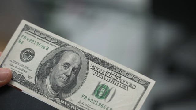 사람이 백달러 지폐를 들고 있는 모습