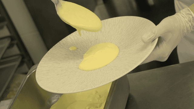 Chef pouring creamy sauce onto a plate