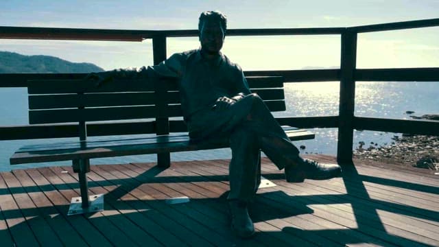 바다를 바라보며 벤치에 홀로 앉은 남자 동상
