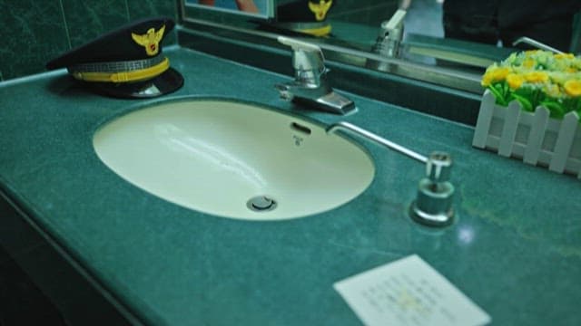 화장실 세면대 앞에서 제복을 정리하는 경찰