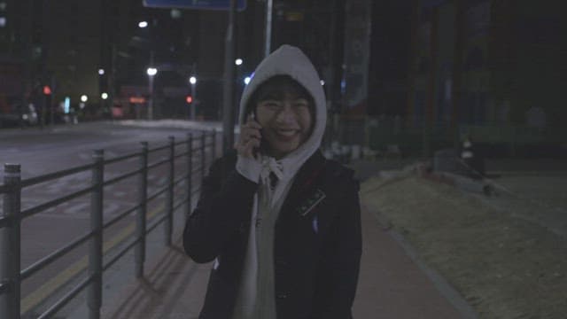 밤에 어두운 거리에서 전화 통화를 하며 걷고 있는 소녀