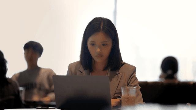 Female office worker focused on her laptop at cafe