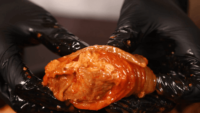 Kimchi jjim, eaten by wrapping kimchi around meat with gloved hands