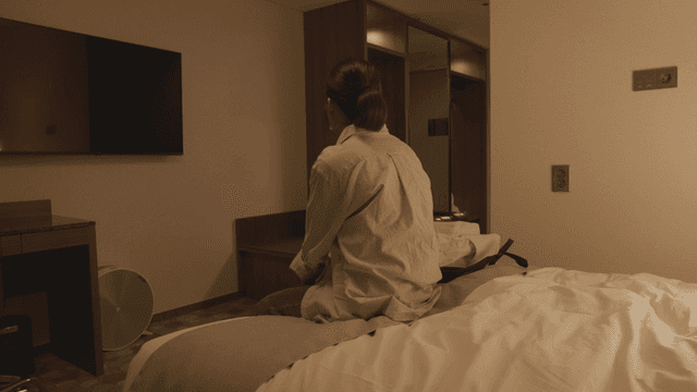 Woman sitting on a bed in a hotel room