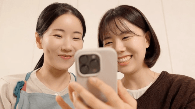 Mother and daughter laughing and playing with their phones