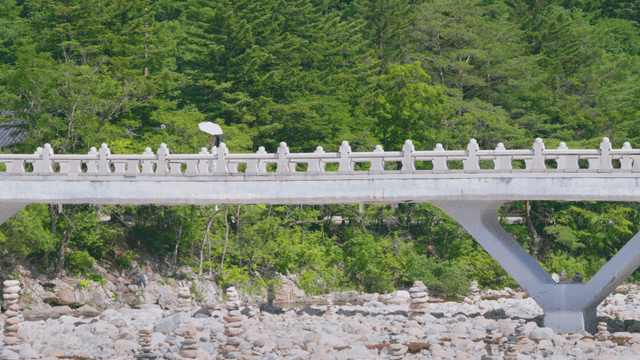 Person with parasol crossing stone bridge