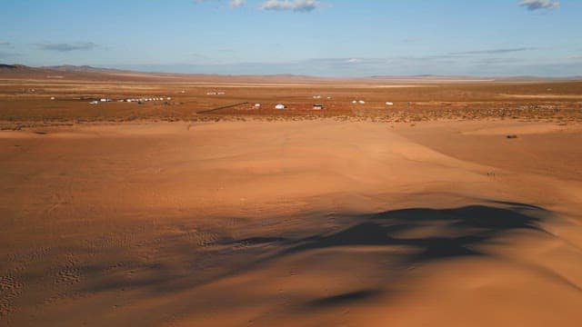 Vast desert landscape with distant yurts