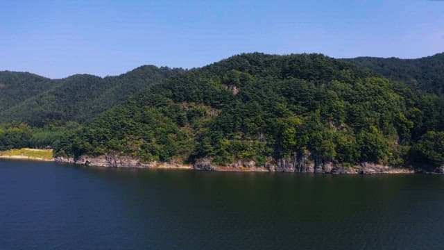 Lush green mountains by a serene river under a clear sky