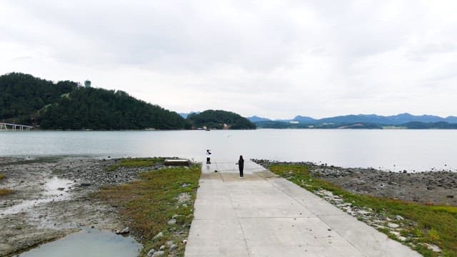 Two people taking pictures of the scenery at the pier on a cloudy day