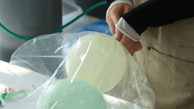 Person who inflates balloon in plastic bag with gas