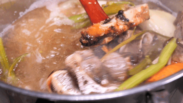 Boiling broth with vegetables and bones