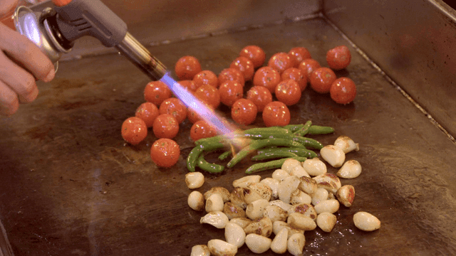 Vegetables being torched on a grill