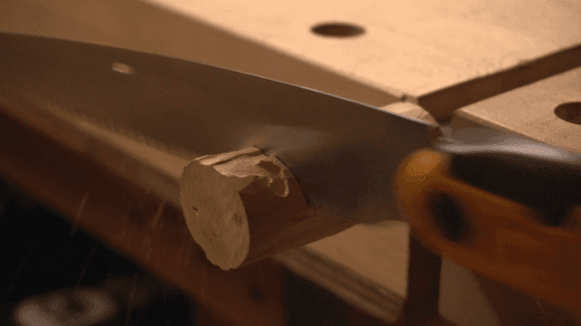 작업대에서 톱으로 나무를 자르는 모습