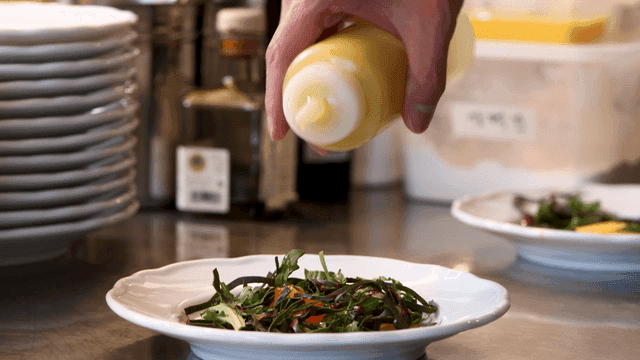 Salad being dressed with yellow sauce