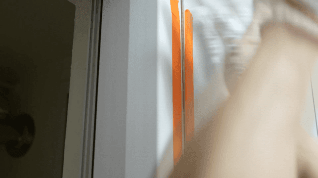 Worker applying masking tape on bathroom tile wall