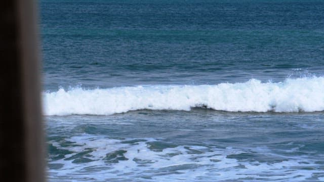 Blue and white waves crashing onto a peaceful beach in the midday
