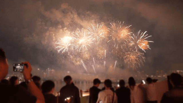People watching fireworks over a cityscape