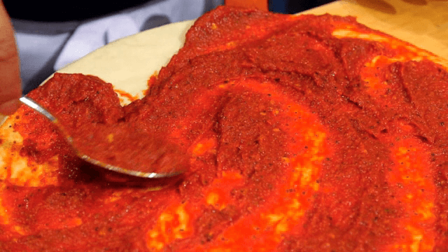 Spreading tomato sauce on pizza dough
