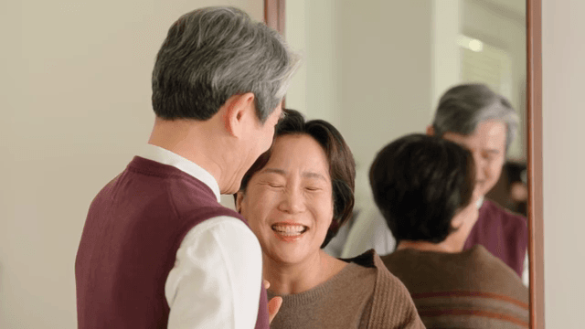 거울 앞에서 대화하며 미소 짓는 노부부