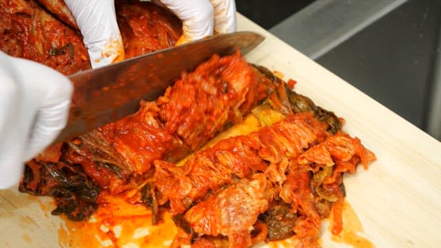 도마에서 썬 김치를 팬에서 볶는 모습