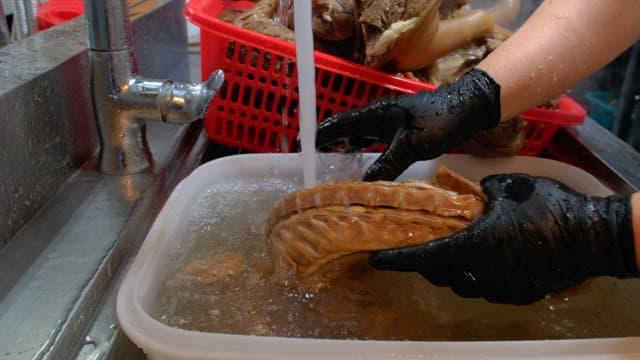 주방에서 삶은 족발과 고기를 물에 헹구는 모습