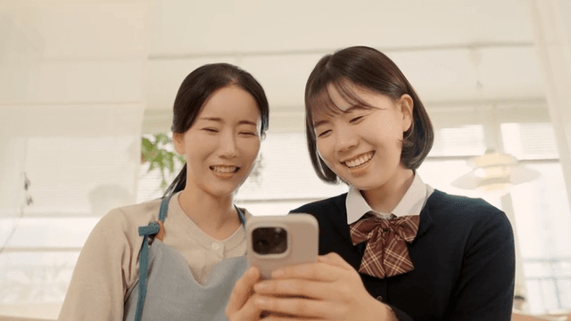 Mother and daughter laughing while looking at their cell phones