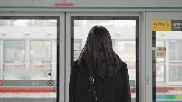 Back of a woman waiting on a subway platform