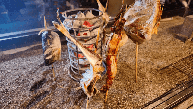 Grilled fish skewers over charcoal