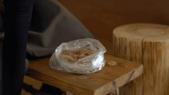 비닐 봉투에 톱밥을 손으로 옮겨 담는 목공예가