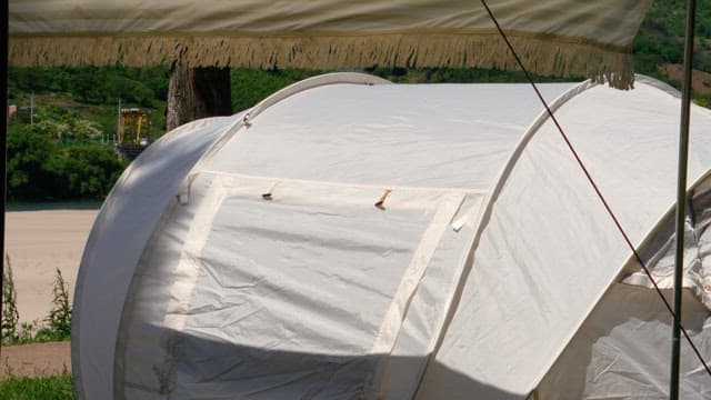 Person setting up a white tent in a scenic outdoor setting