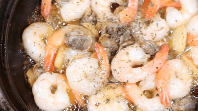 팬에서 새우와 꼬막이 지글거리는 모습