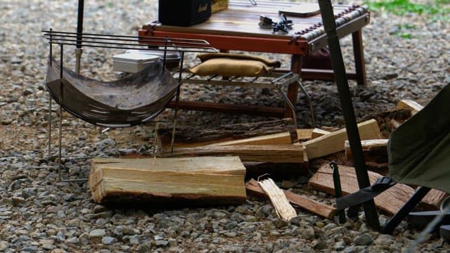 Preparing firewood and portable grill with gloved hands in outdoor setting