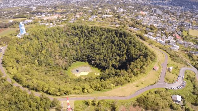 도시 속 숲이 우거진 분화구의 항공 뷰