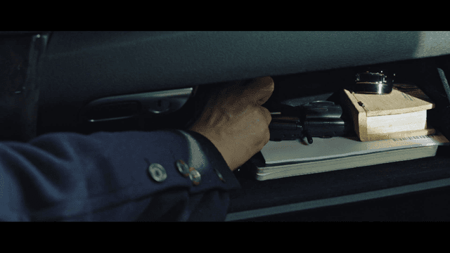 A hand reaching into a car glove compartment