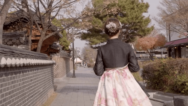 한복을 입은 여성이 전통 한국 거리를 걷는 모습
