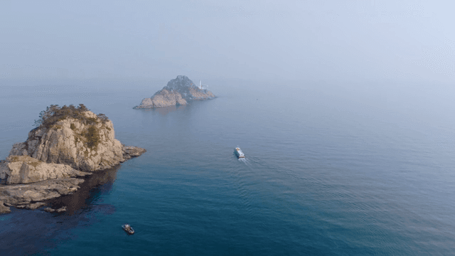 바위 섬과 배가 있는 고요한 바다