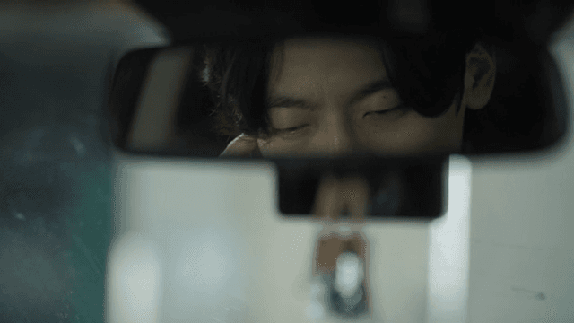Man seen through the rearview mirror while talking on the phone