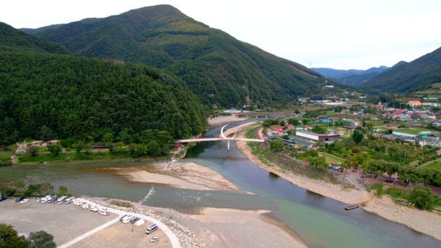 Scenic view of a serene countryside with a crescent-shaped bridge spanning over a peaceful river